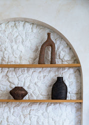 Decorative wooden shelves with ceramic vases against a textured white wall.