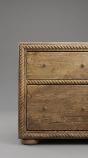 Wooden dresser with rope detailing on a gray background