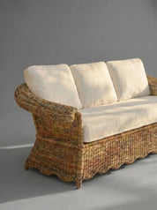 Wicker sofa with white cushions on a gray background