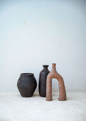 Three ceramic vases of different shapes and sizes on a white surface with a light gray background