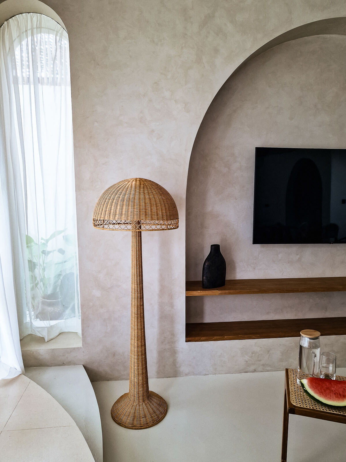 Rattan floor lamp in a living room with a television and decorative items.