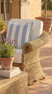Wicker chair with striped cushion and lavender plant on a patio