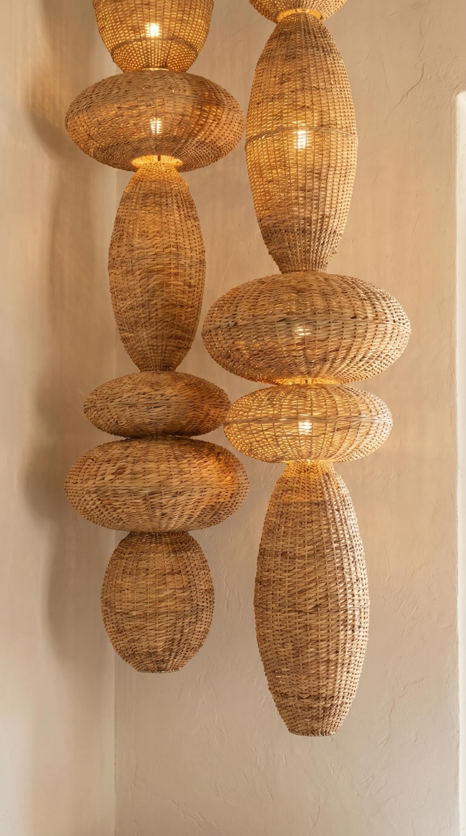 Woven rattan pendant lights hanging against a neutral wall.