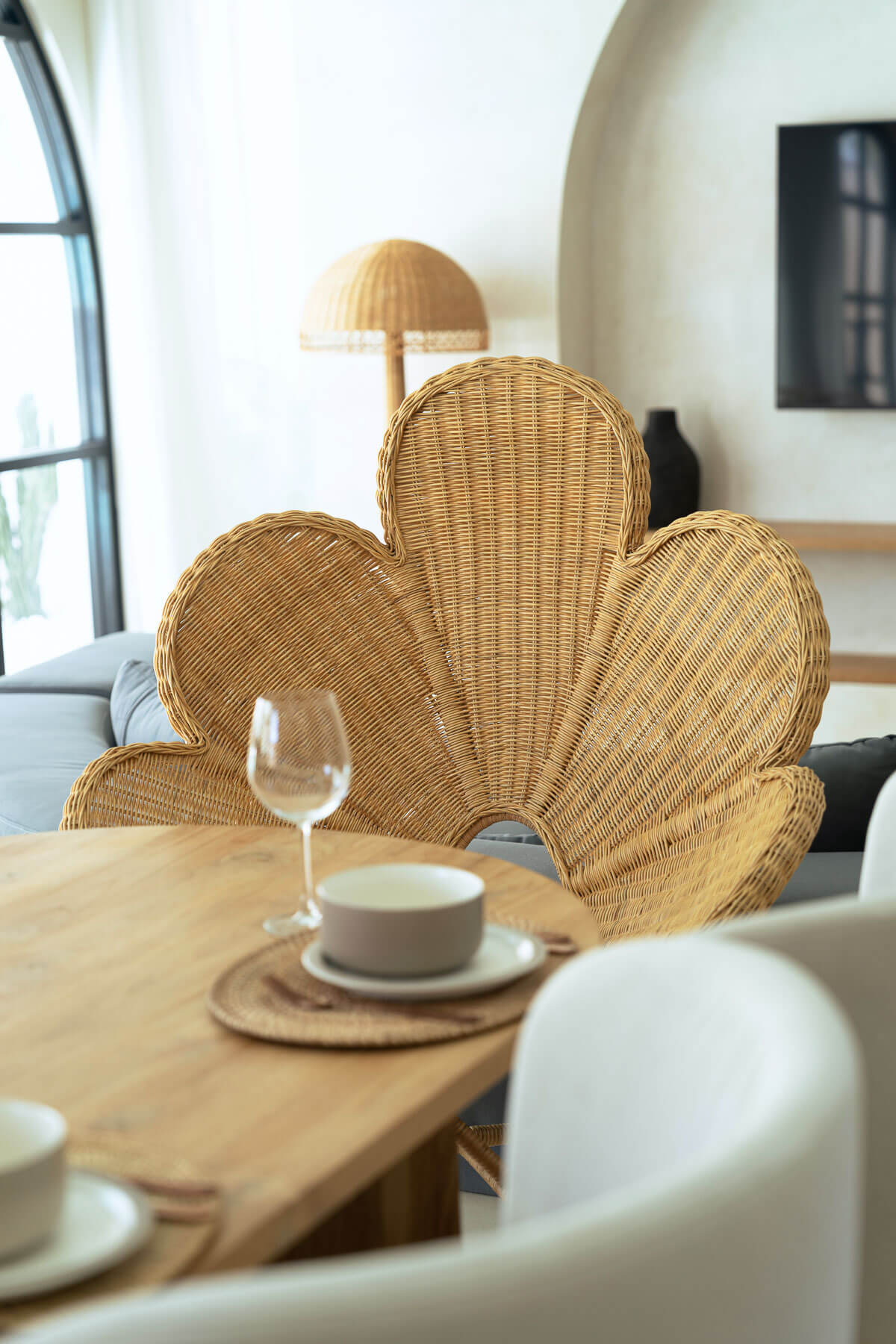 Wicker chair with a modern interior setting, featuring a table with a cup and glass.