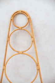 Rattan plant stand with circular design on a light gray background