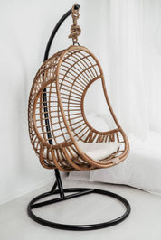 Wicker hanging chair with black stand on a white background
