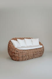 Wicker chair with white cushions on a plain background