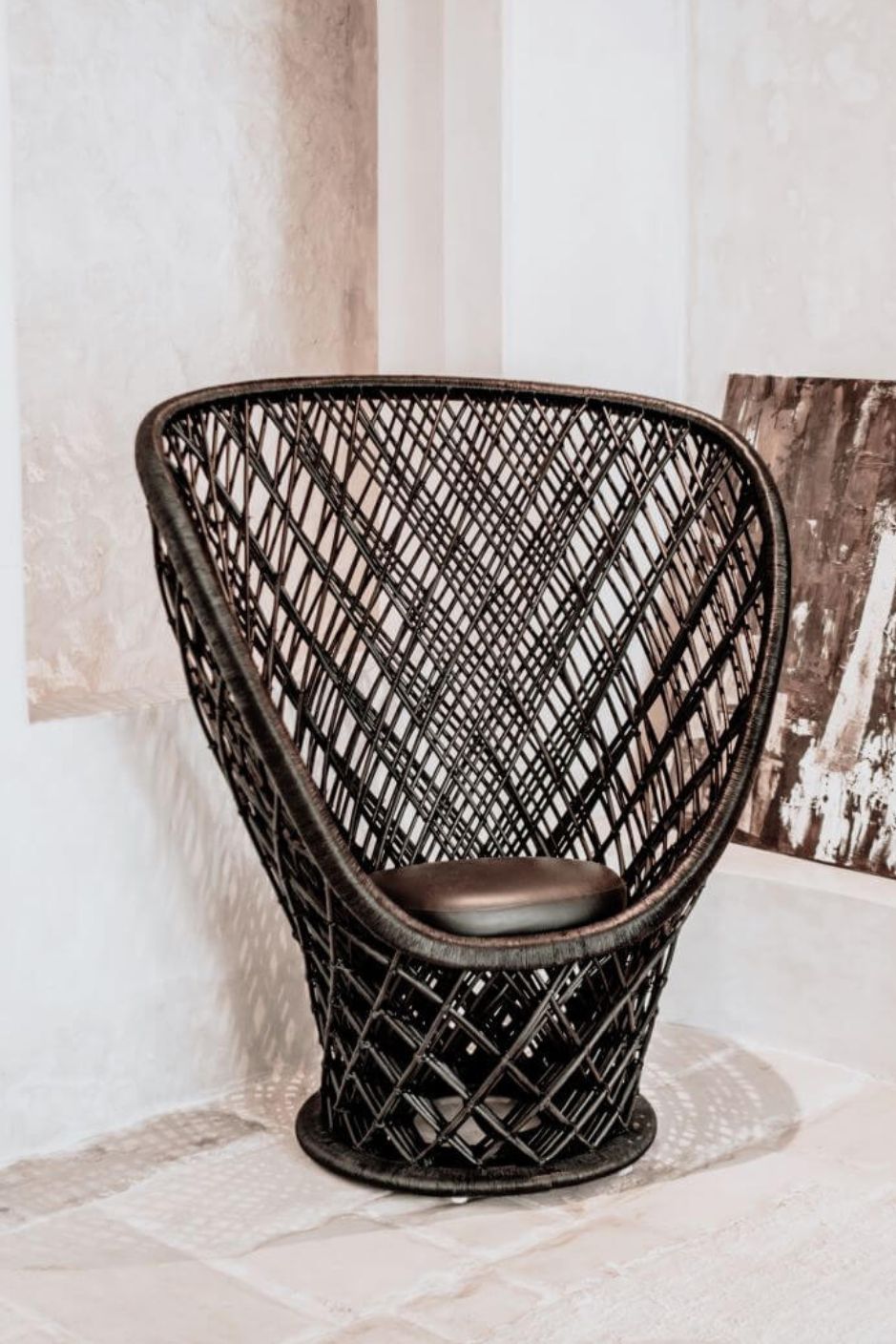 Wicker chair with a textured backrest and cushion on a light wooden floor.