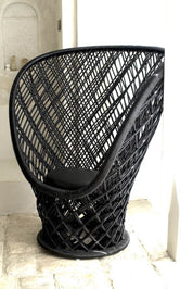Black woven chair with a cushion on a stone floor