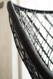 Close-up of a black woven chair with a blurred background