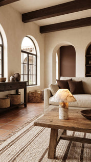 Living room with rustic decor, including a sofa, coffee table, and arched windows.