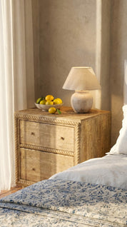 Wooden nightstand with a lamp and fruit bowl in a bedroom setting