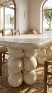 Dining table with spherical stone base in a bright room with large windows.