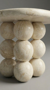 Decorative table with spherical stone legs on a gray background