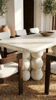 Dining table with marble top and wooden legs in a room with chairs and decor.