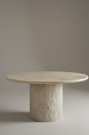 round marble dining table with sculptural stone pedestal base
