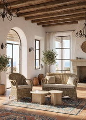 Cozy living room with wicker furniture, wooden beams, and large windows.