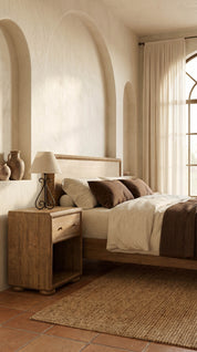 Cozy bedroom with wooden nightstand, bed, and lamp.