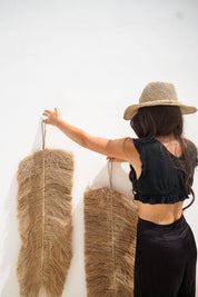 Person holding two large feathered wall hangings against a white background