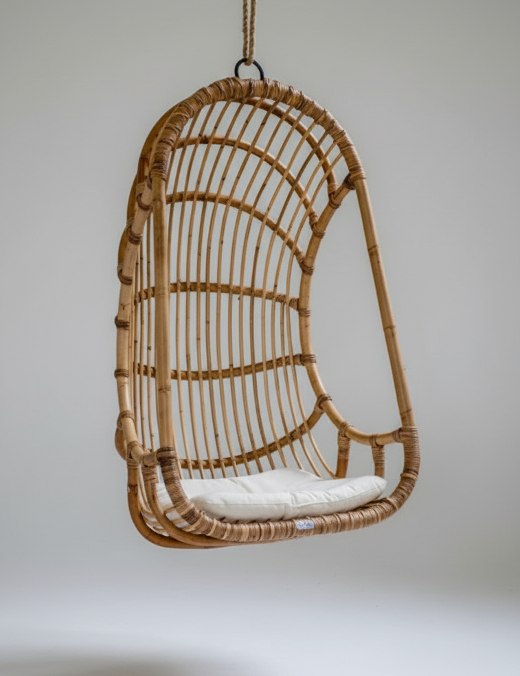 Wicker hanging chair with a white cushion on a plain background