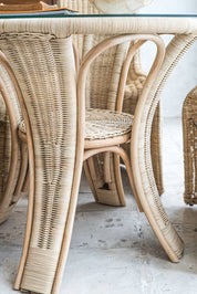 Oriana Ori round rattan table with woven shelf and braided legs, topped with thick glass, showcasing handcrafted natural rattan design and artisanal details
