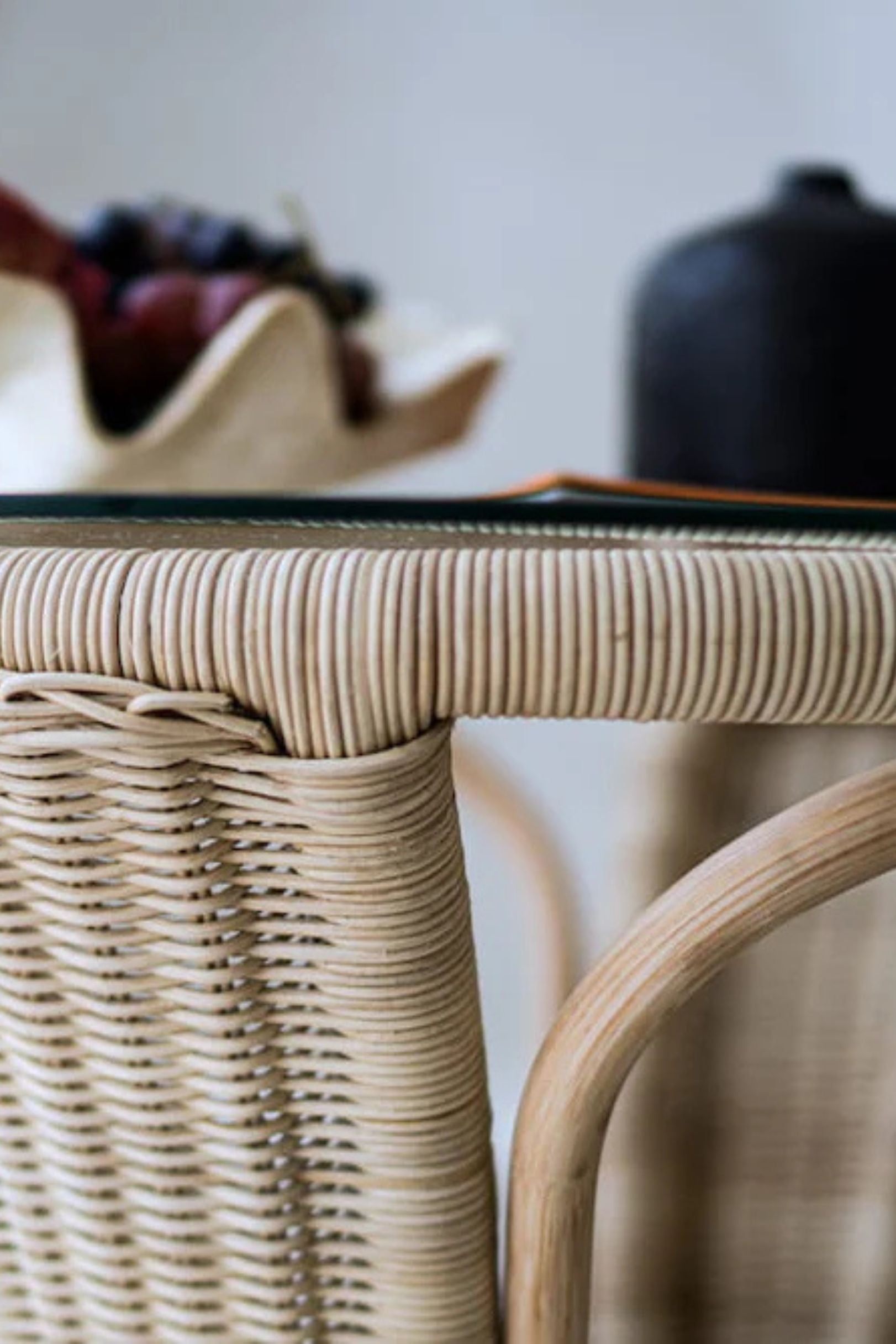 Oriana Ori round rattan table with woven shelf and braided legs, topped with thick glass, showcasing handcrafted natural rattan design and artisanal details