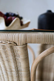 Oriana Ori round rattan table with woven shelf and braided legs, topped with thick glass, showcasing handcrafted natural rattan design and artisanal details