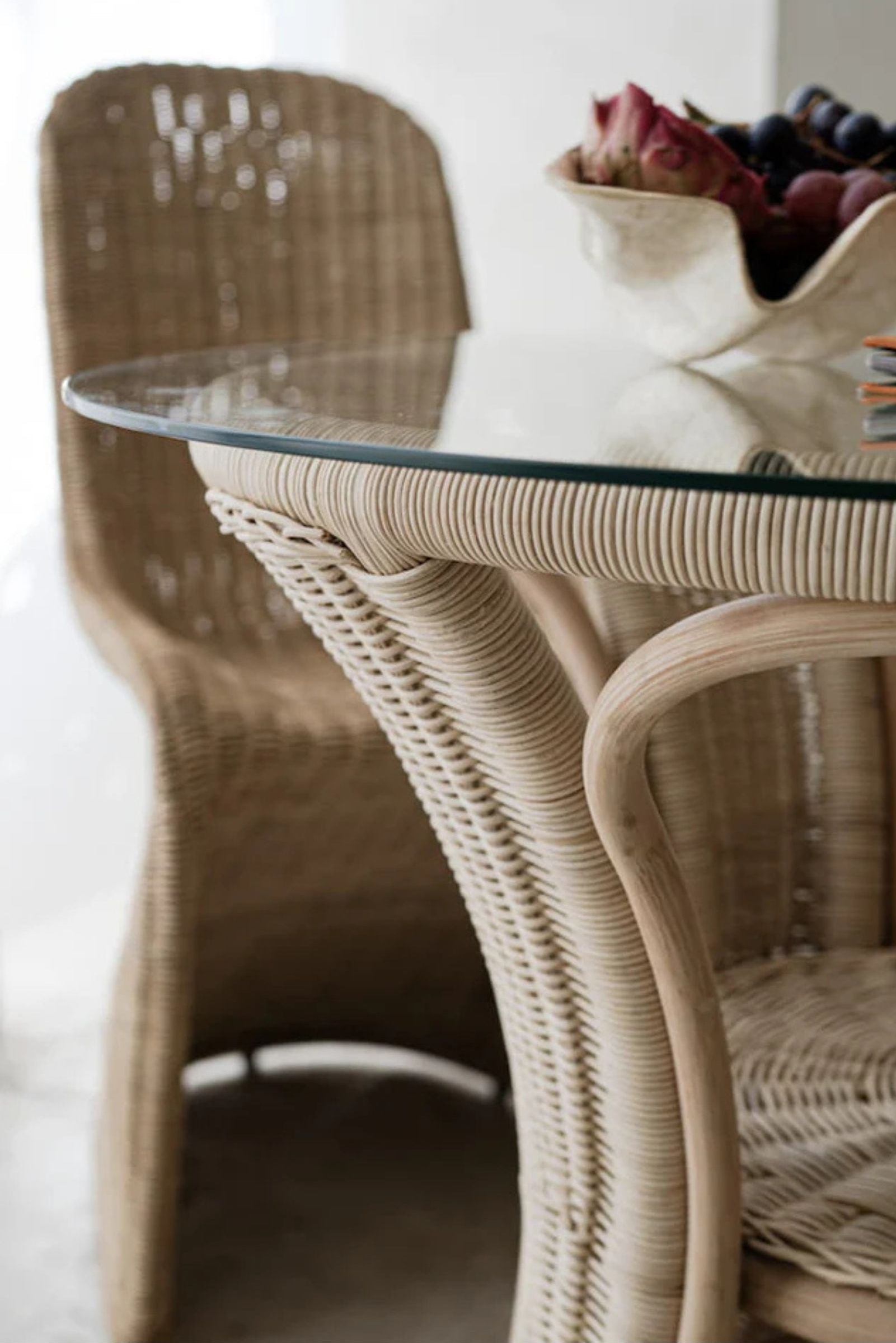 Oriana Ori round rattan table with woven shelf and braided legs, topped with thick glass, showcasing handcrafted natural rattan design and artisanal details