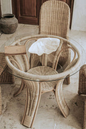 Oriana Ori round rattan table with woven shelf and braided legs, topped with thick glass, showcasing handcrafted natural rattan design and artisanal details