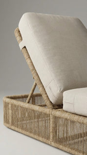 Wicker chair with beige cushion on a neutral background