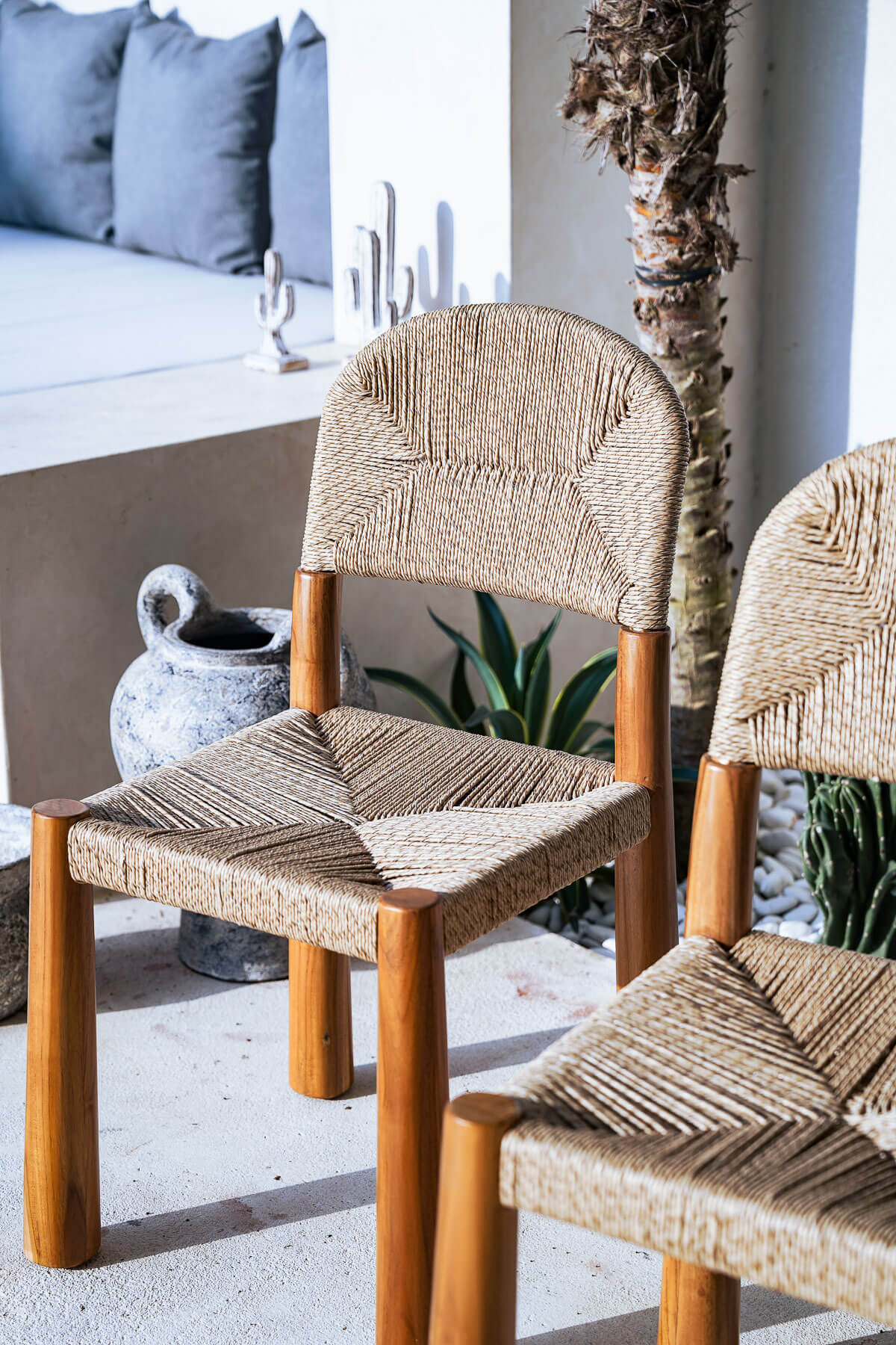 Two woven chairs on a patio with a neutral background