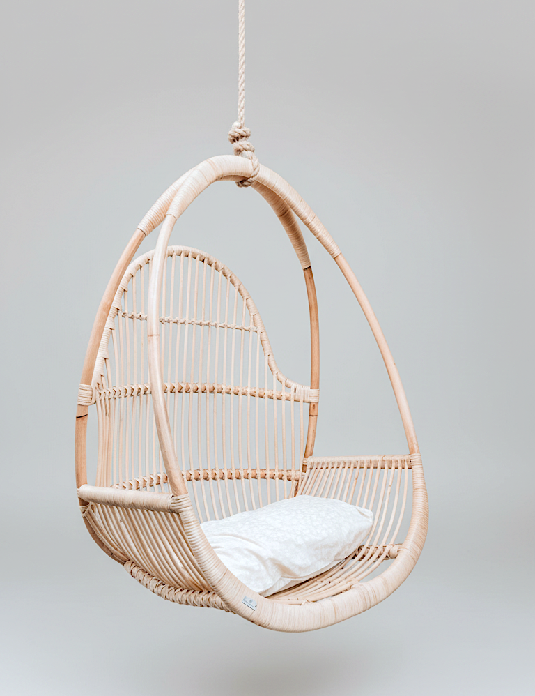 Rattan hanging chair with a white cushion on a light gray background