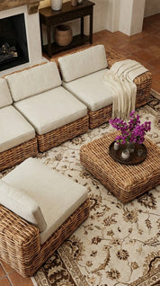 Wicker outdoor furniture set with cushions on a patterned rug.