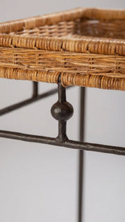 Wicker basket on a metal stand with a plain background