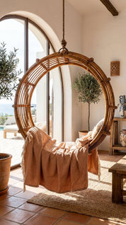 Rattan chair with a blanket in a sunlit room with large windows.