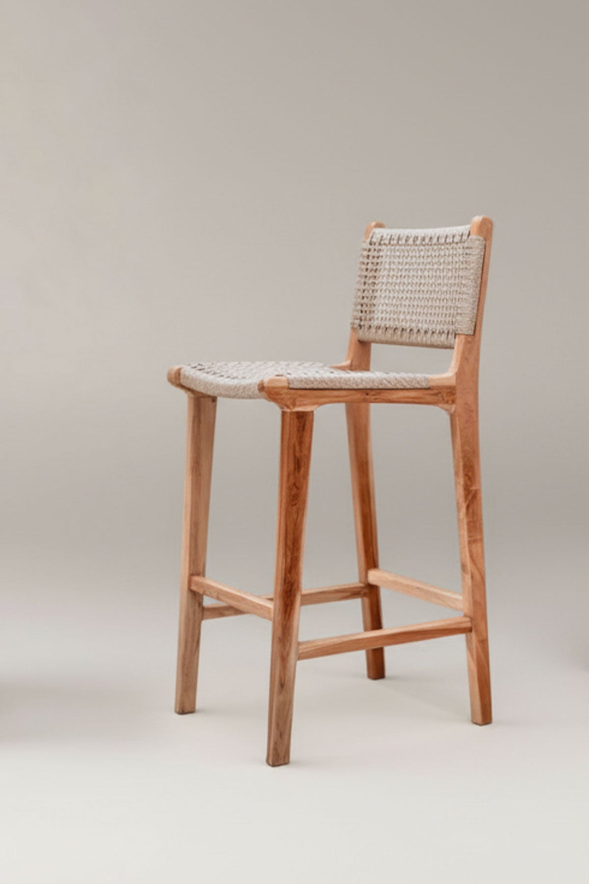 Wooden bar stool with woven backrest on a plain background