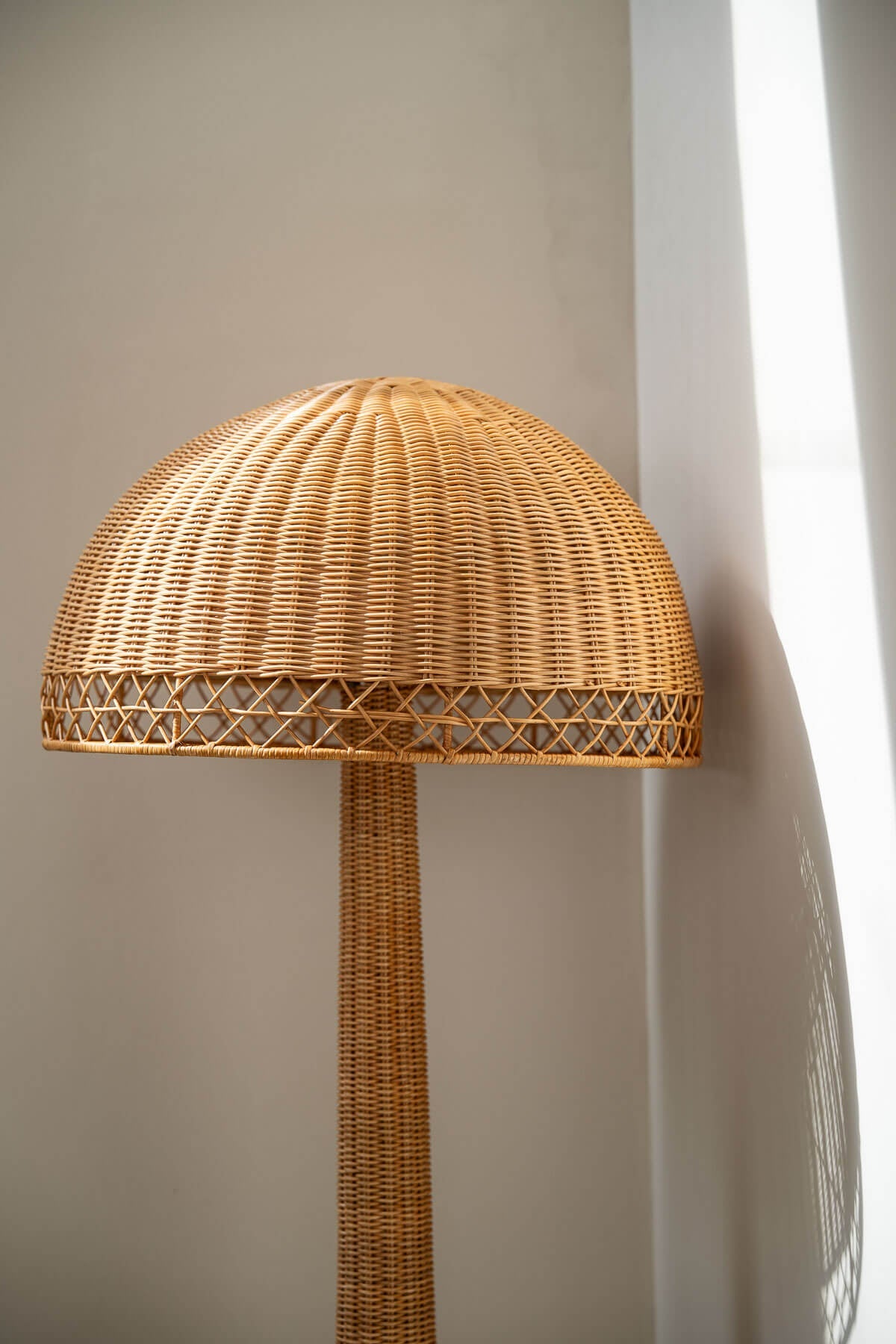 Wicker lamp with a dome-shaped shade against a neutral wall.
