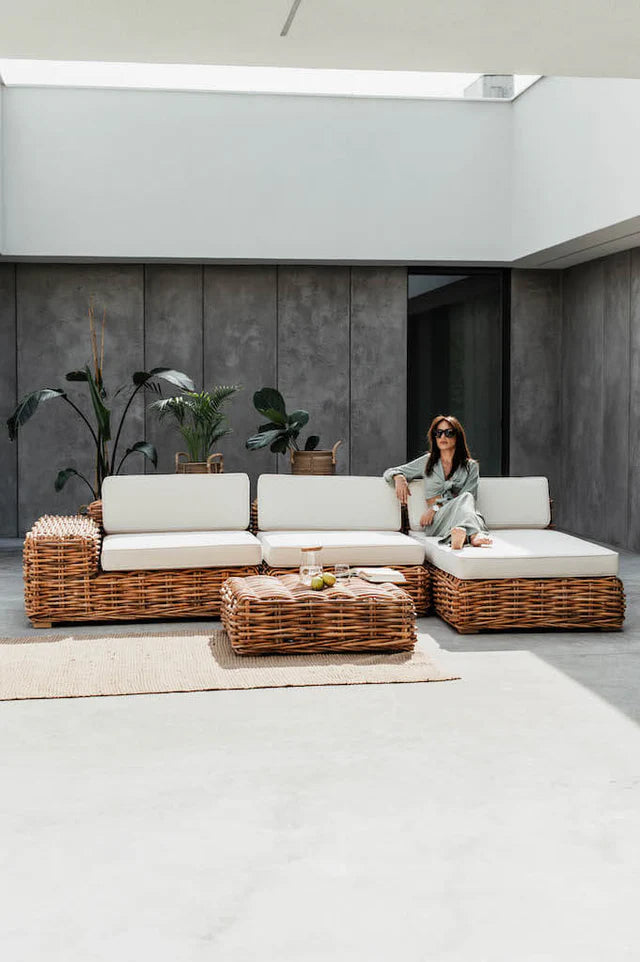 Woman sitting on a modern outdoor sofa set with a neutral color palette.