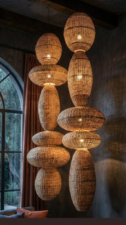 Woven rattan pendant lights hanging in a room with a window and curtain.