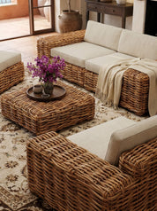 Cozy living room with wicker furniture, a fireplace, and large windows overlooking a scenic view.