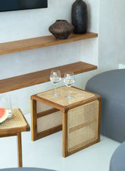 Wooden side table with wicker accents next to a gray sofa in a modern living room.