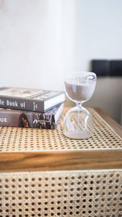 Hourglass and books on a textured surface with a neutral background