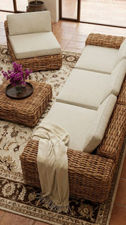 Wicker outdoor furniture set with white cushions on a patterned rug.