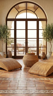 Relaxation area with wicker chairs and a large arched window.
