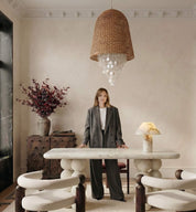 Woman standing in a stylish room with a modern dining table and chairs.
