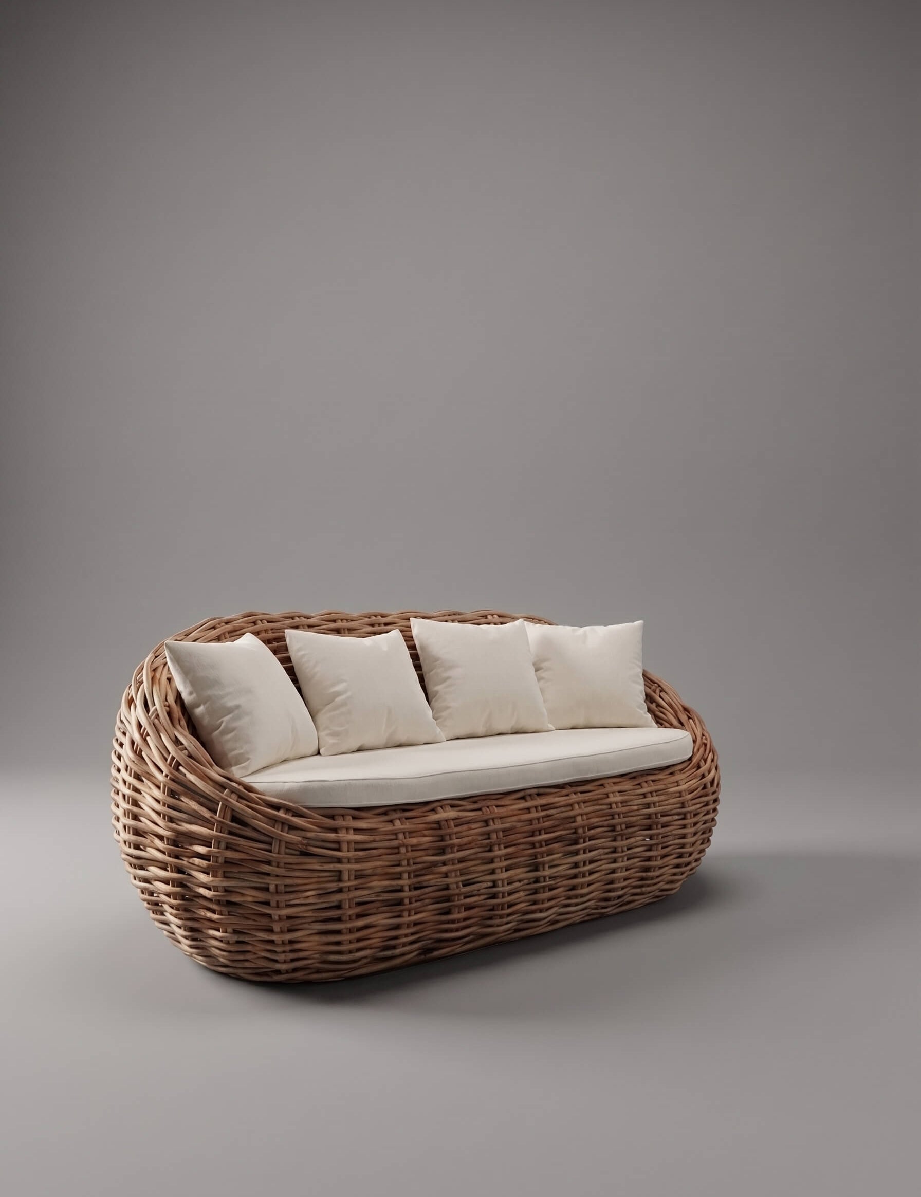 A woven rattan or wicker outdoor daybed with a rounded basket-like frame, upholstered in off-white fabric, and supported by four matching square pillows, set against a solid gray studio background.