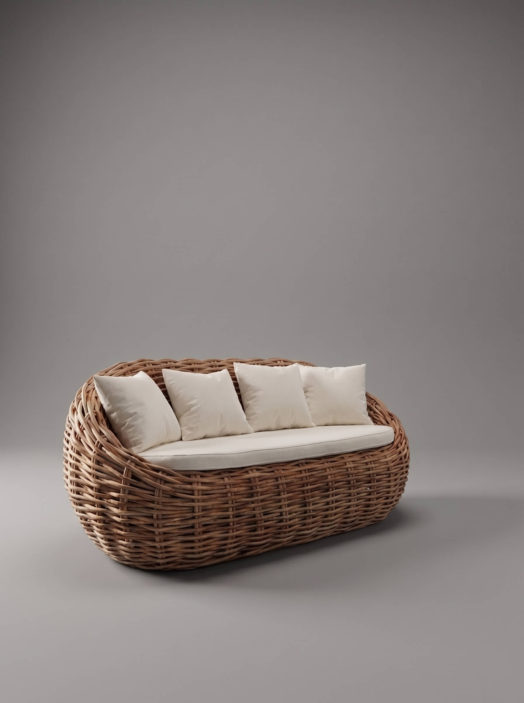 A woven rattan or wicker outdoor daybed with a rounded basket-like frame, upholstered in off-white fabric, and supported by four matching square pillows, set against a solid gray studio background.