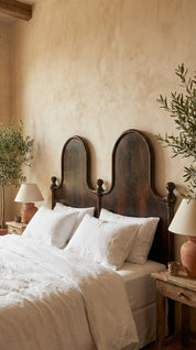 Bedroom with wooden headboard, white bedding, and decorative lamps.