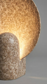 Close-up of a textured lamp with a warm glow on a gray background