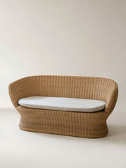 Wicker chair with a white cushion on a plain background